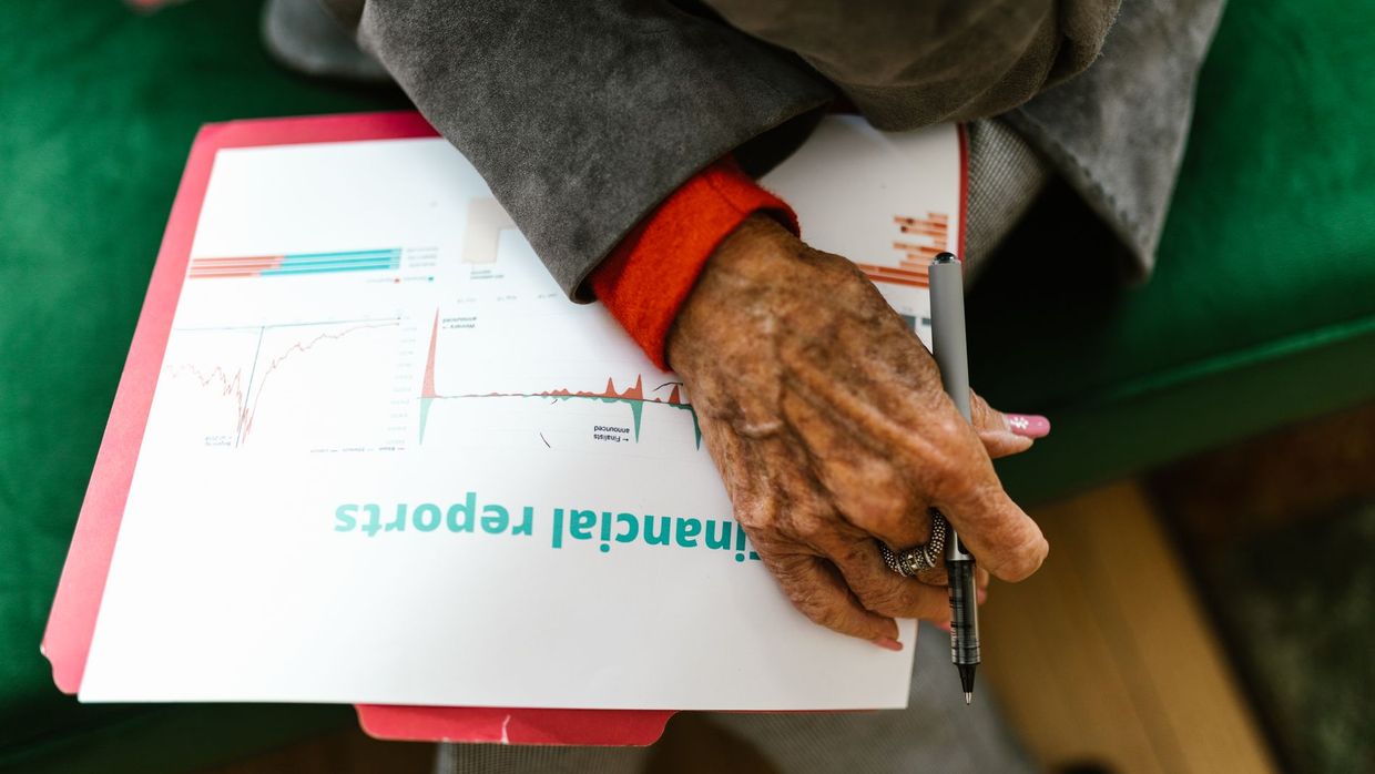 SEO versus data analysis: close-up of an elderly woman holding a pen with a financial report